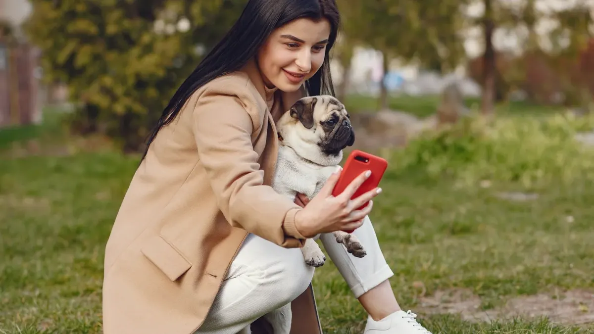 A dog owner on the phone near a kitchen counter with a pill bottle nearby